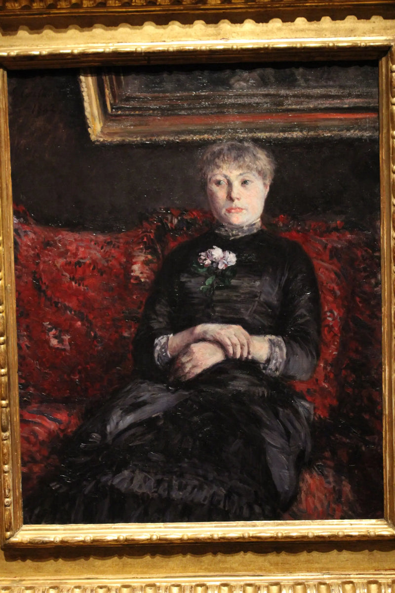 Frau sitzt auf einem Sofa mit roten Blumen - Gustave Caillebotte